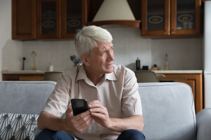How Do I Know When It’s Time to Buy a New Furnace? Worried senior smartphone user getting bad, concerning news message, holding mobile phone, looking away, feeling stressed, anxious, thinking over problems.